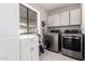 A laundry room featuring modern washer and dryer units, cabinets, and a sink at 1002 E Topeka Dr, Phoenix, AZ 85024