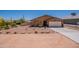 Single story home boasting desert landscaping, rocks, and a large driveway leading to a two-car garage at 10177 E La Palma Ave, Gold Canyon, AZ 85118
