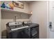 This laundry area includes a gray washer and dryer and additional shelving for storage at 10177 E La Palma Ave, Gold Canyon, AZ 85118