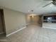 Open-concept living room and kitchen with neutral tile flooring, dark kitchen cabinets, and dining area at 10736 W Swayback Pass, Peoria, AZ 85383