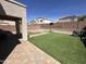 Well-kept backyard with turf, paved patio, and a clear blue sky at 11460 W Eden Mckenzie Dr, Surprise, AZ 85378