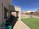 View of backyard featuring covered patio with table and brick accents along artificial turf at 11460 W Eden Mckenzie Dr, Surprise, AZ 85378