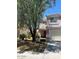 Two-story home featuring a tan stucco facade, white garage door, and mature landscaping at 11460 W Eden Mckenzie Dr, Surprise, AZ 85378