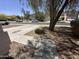 View of the walkway to a single Gathering home surrounded by desert landscaping and mature trees at 11460 W Eden Mckenzie Dr, Surprise, AZ 85378