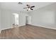 Spacious bedroom with hardwood floors, neutral paint, a ceiling fan, and direct access to the ensuite bath at 14200 W Larkspur Dr, Surprise, AZ 85379