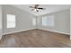 Neutral bedroom with wood-look floors, ceiling fan, and bright windows with classic blinds at 14200 W Larkspur Dr, Surprise, AZ 85379