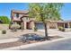 View of a two-story home showcasing a tile roof, attached two-car garage, and desert landscaping at 14200 W Larkspur Dr, Surprise, AZ 85379