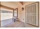 Covered front porch with a security screen door, accent table, and outdoor light fixture at 14200 W Larkspur Dr, Surprise, AZ 85379