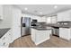 Kitchen with white cabinetry, stainless steel appliances, dark countertops, and wood-look flooring at 14200 W Larkspur Dr, Surprise, AZ 85379