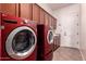 Well-organized laundry room featuring a red washer/dryer set, ample cabinet space, and a convenient folding area at 14552 S 182Nd Dr, Goodyear, AZ 85338