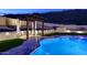 Stunning backyard pool and water feature, accented by elegant hardscape and ambient lighting, creating a magical nighttime experience at 14552 S 182Nd Dr, Goodyear, AZ 85338