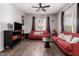 Inviting living room featuring bright natural light, wood floors, red sofas, and a ceiling fan at 14575 W Mountain View Blvd # 11220, Surprise, AZ 85374