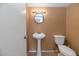Simple bathroom featuring pedestal sink, standard toilet, round mirror, and four-light vanity at 17819 N 46Th Dr, Glendale, AZ 85308