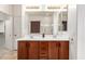 Bathroom with wooden vanity, double sinks, and large mirror with sconce lighting at 18072 W Paradise Ln, Surprise, AZ 85388