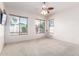 Bright bedroom with carpet, ceiling fan, and multiple windows overlooking the greenery outside at 18072 W Paradise Ln, Surprise, AZ 85388