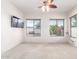 Bright bedroom with carpet, ceiling fan, and multiple windows with greenery outside at 18072 W Paradise Ln, Surprise, AZ 85388