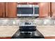 Close-up of a range with a tiled backsplash and modern microwave in the kitchen at 18072 W Paradise Ln, Surprise, AZ 85388