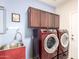 Laundry room features cabinets, sink, and a red washer and dryer at 18072 W Paradise Ln, Surprise, AZ 85388