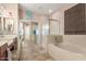 Well-lit bathroom features a soaking tub, glass-enclosed shower, and tiled flooring at 18482 W Marconi Ave, Surprise, AZ 85388
