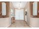 View of a tiled foyer with a mirror, table, lamps and a decorative front door at 18482 W Marconi Ave, Surprise, AZ 85388