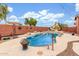 Backyard swimming pool with water features surrounded by a decorative brick fence and lounge seating area at 18482 W Marconi Ave, Surprise, AZ 85388