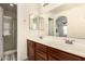 Well-lit bathroom boasts double sinks, wood cabinets, and a glass door shower at 20045 N 49Th Dr, Glendale, AZ 85308