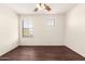 Clean, empty bedroom with hardwood floors, ceiling fan, and two windows at 20045 N 49Th Dr, Glendale, AZ 85308