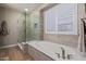 Bathroom showcasing a soaking tub, glass shower, and plantation shutters providing privacy and light at 20420 N 93Rd Dr, Peoria, AZ 85382