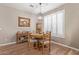 Dining room with a round table, light fixture, wood floors, and natural light from the window shutters at 20420 N 93Rd Dr, Peoria, AZ 85382