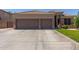 Inviting front view featuring a three car garage with brick accents, large driveway, and meticulously maintained landscaping at 20420 N 93Rd Dr, Peoria, AZ 85382