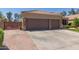 Inviting front view featuring a three car garage with brick accents, large driveway, and meticulously maintained landscaping at 20420 N 93Rd Dr, Peoria, AZ 85382