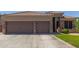Inviting front view featuring a three car garage with brick accents, large driveway, and meticulously maintained landscaping at 20420 N 93Rd Dr, Peoria, AZ 85382