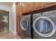 Close-up of high-efficiency washer and dryer under wood cabinets in this home's laundry room at 20420 N 93Rd Dr, Peoria, AZ 85382