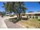 Well-kept one-story home featuring a two-car garage, manicured lawn, and mature trees at 21218 N Aurora Dr, Sun City West, AZ 85375