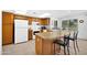 Bright kitchen with wooden cabinetry, white appliances, a breakfast bar, and an adjacent dining area at 21218 N Aurora Dr, Sun City West, AZ 85375