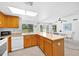 Open concept kitchen with wooden cabinets, a breakfast bar, and an adjacent dining area with natural lighting at 21218 N Aurora Dr, Sun City West, AZ 85375