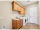 Well-appointed laundry room featuring wooden cabinets, sink and modern washer and dryer units at 2609 W Lavitt Ln, Phoenix, AZ 85086