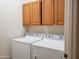 Well-lit laundry room with a washing machine, dryer, and wooden cabinets for storage at 2611 E San Paulo Dr, Casa Grande, AZ 85194