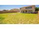 Expansive grassy backyard, perfect for outdoor activities, with a view of the tan two-story house and neighboring homes at 34949 N Spur Cir, San Tan Valley, AZ 85144