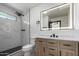 Bathroom with wood vanity, black fixtures, decorative mirror, and tile lined shower at 3802 N 48Th Dr, Phoenix, AZ 85031