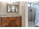 Bathroom featuring granite countertop, wood cabinets, framed mirror and tiled shower with soap niche at 4813 W Belmont Ave, Glendale, AZ 85301