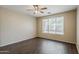 Neutral bedroom featuring a ceiling fan, large window, and dark wood-look floors at 5926 W Questa Dr, Glendale, AZ 85310