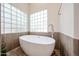 This modern bathroom displays a freestanding tub with a sleek faucet set against a bright window with decorative glass blocks at 6135 E Aire Libre Ln, Scottsdale, AZ 85254