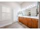 Bright bathroom features a double sink vanity, tiled floor, plantation shutters, and an exit door at 6135 E Aire Libre Ln, Scottsdale, AZ 85254