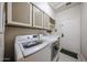 Clean and functional laundry room with modern washer and dryer units, upper cabinets, and a utility sink at 6135 E Aire Libre Ln, Scottsdale, AZ 85254