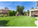 Backyard featuring artificial turf, a stone fireplace, disc golf basket, and covered patio at 6870 S Crestview Dr, Gilbert, AZ 85298
