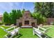 Outdoor stone fireplace with stacked wood, artificial grass, and Adirondack chairs at 6870 S Crestview Dr, Gilbert, AZ 85298