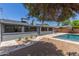 Expansive backyard featuring a pool, lush greenery, and a charming outdoor dining setup at 7727 E 4Th St, Scottsdale, AZ 85251