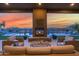Covered patio with a fireplace, comfortable seating, manicured lawn and a view of the pool and mountains at 8300 E Lone Mountain Rd, Scottsdale, AZ 85266
