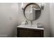 Modern powder room featuring an elegant wood vanity and a round mirror with stylish wall sconces at 8312 N Golf Dr, Paradise Valley, AZ 85253